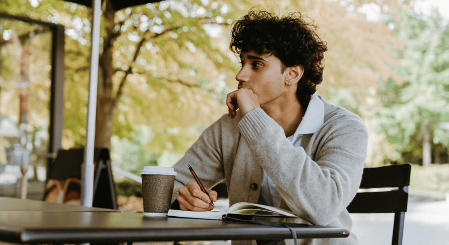 young man writing at a coffee shop