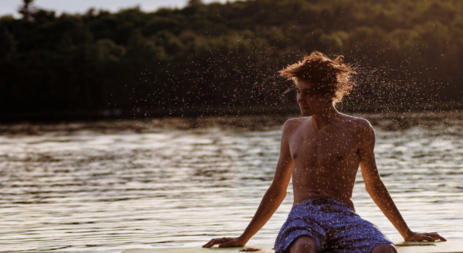 Young man shaking his hair off after getting out of the water