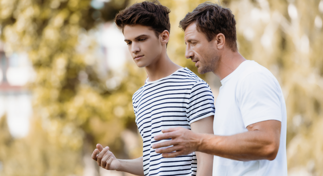 young man walking and talking with an older man