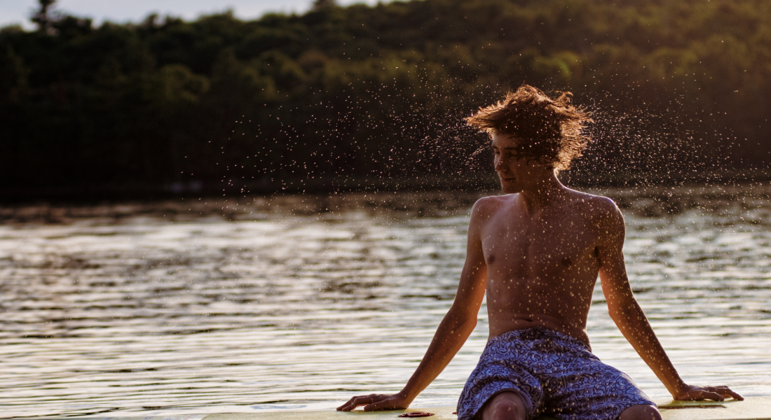 Young man shaking his hair off after getting out of the water